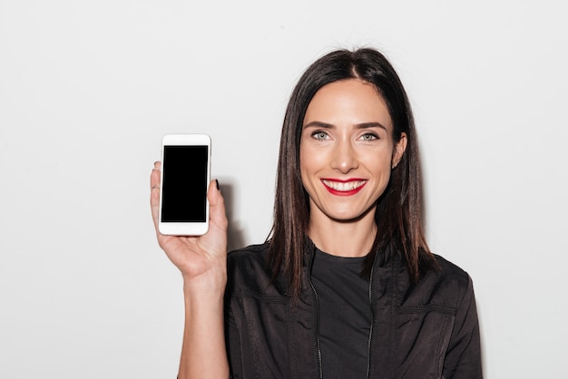 Cheerful woman with red lips showing display of mobile phone.