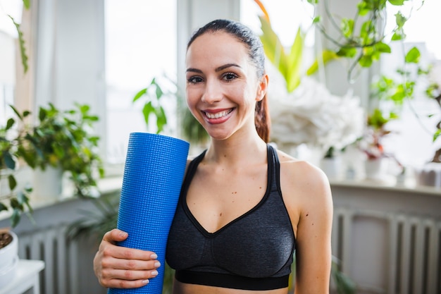 Cheerful woman with yoga mat