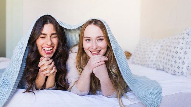 Cheerful women under blanket