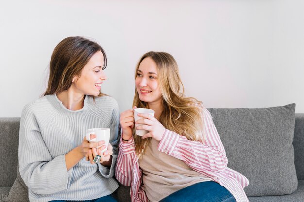 Cheerful women drinking on sofa