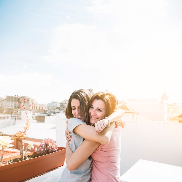 Cheerful women hugging on street