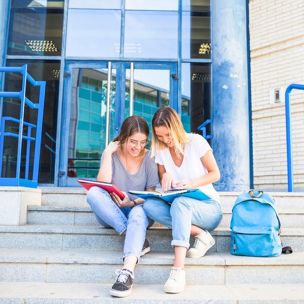 Cheerful women studying on university steps