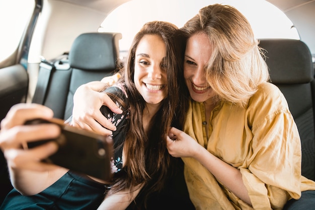 Cheerful women taking selfie in car