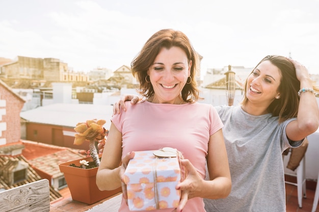 Cheerful women with gift on street