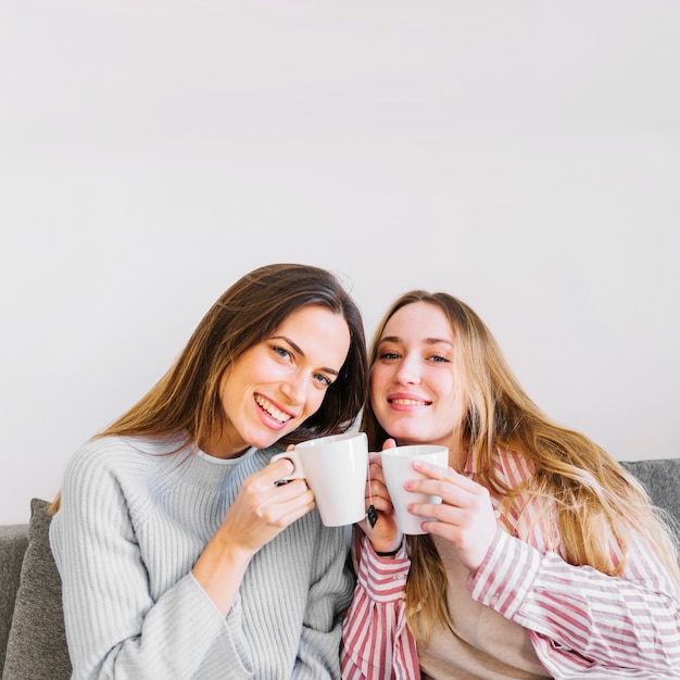 Cheerful women with mugs looking at camera