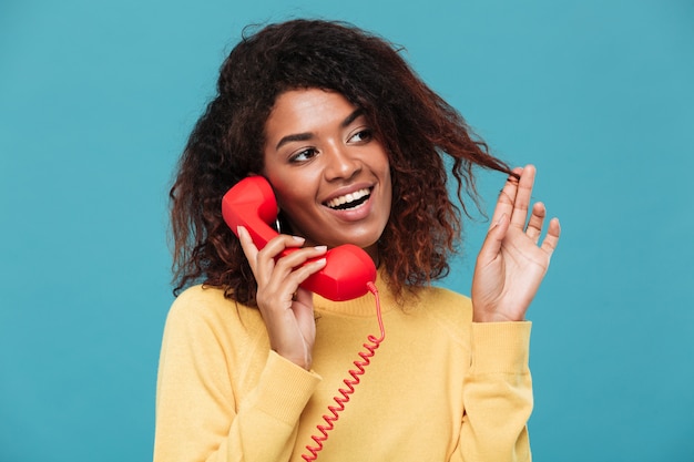 Cheerful young african lady talking by telephone.