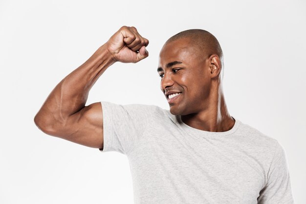 Cheerful young african man showing biceps.