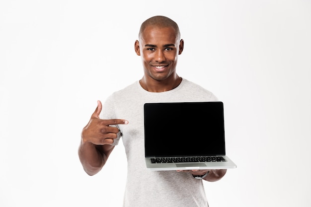 Cheerful young african man showing display of laptop