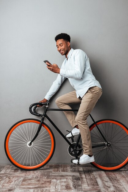 Cheerful young african man standing over grey wall chatting