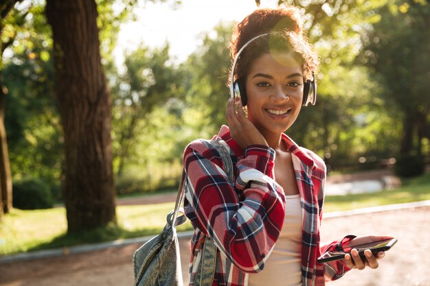 Cheerful young african woman walking chatting by phone.