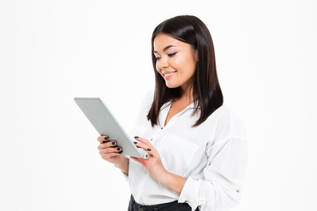 Cheerful young asian lady chatting by tablet computer