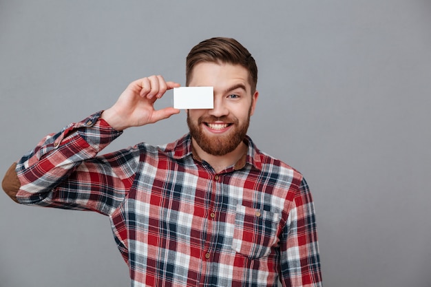 Веселый молодой бородатый человек, держащий пустую визитную карточку