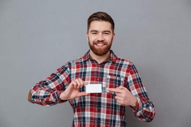 Free photo cheerful young bearded man with blank business card