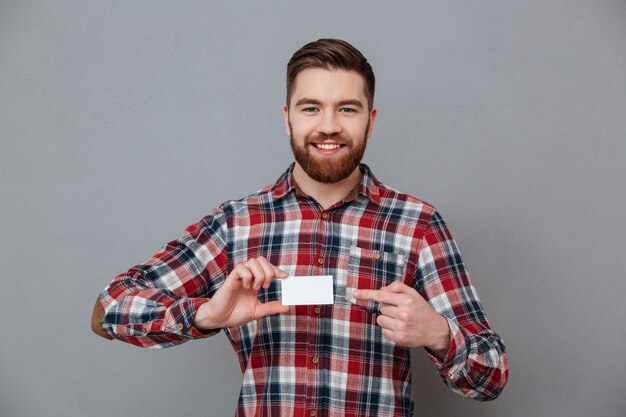 Cheerful young bearded man with blank business card