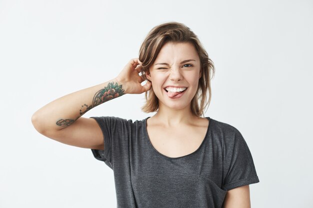 Cheerful young beautiful girl smiling winking showing tongue .