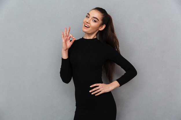 Cheerful young beautiful woman showing ok gesture