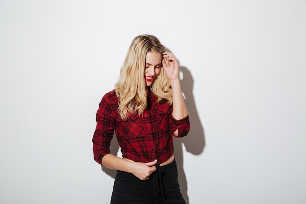 Cheerful young blonde woman standing isolated