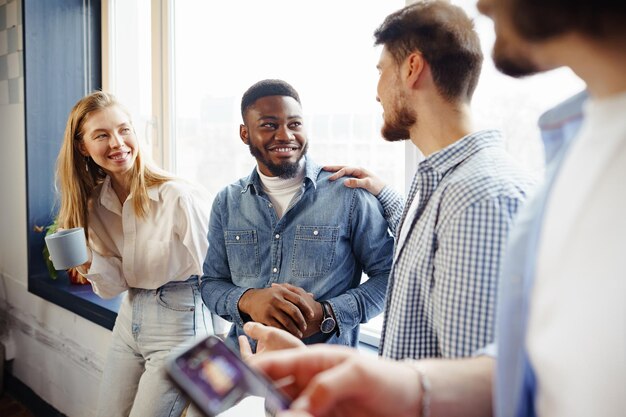 Cheerful young business people have a talk during coffee break in office