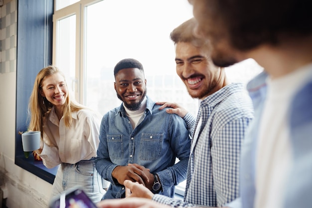 Cheerful young business people have a talk during coffee break in office