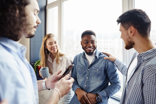 Free photo cheerful young business people have a talk during coffee break in office