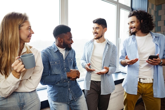 Free photo cheerful young business people have a talk during coffee break in office