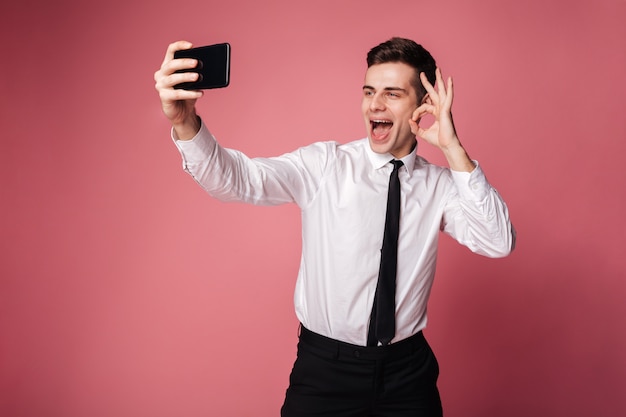 Cheerful young businessman showing okay gesture.