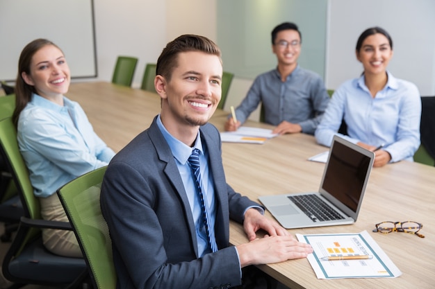 Cheerful young businessman sitting at seminar