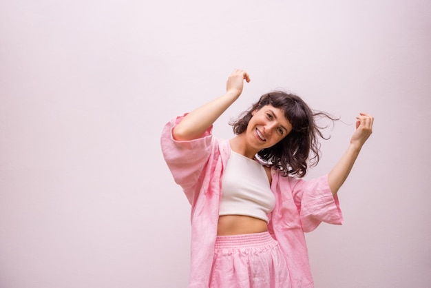 Cheerful young caucasian brunette in top shirt and pants is actively moving posing on white background People emotions lifestyle and fashion concept