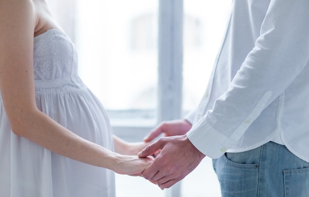 Cheerful young couple dressed in white standing at home