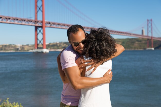 Cheerful young couple hugging near river