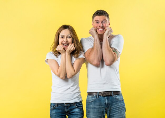 Cheerful young couple looking to camera against yellow backdrop