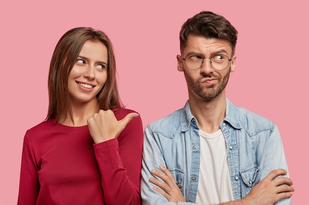 cheerful young couple posing against the pink wall