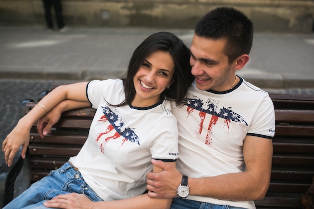 Free photo cheerful young couple posing on bench