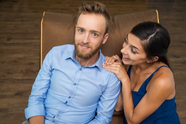 Cheerful young couple sitting on couch and smiling