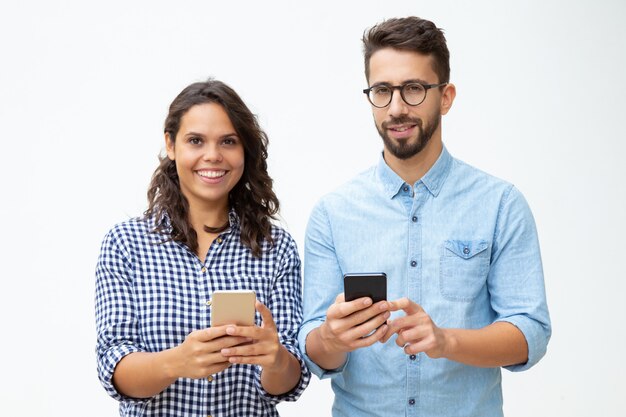 Cheerful young couple using smartphones