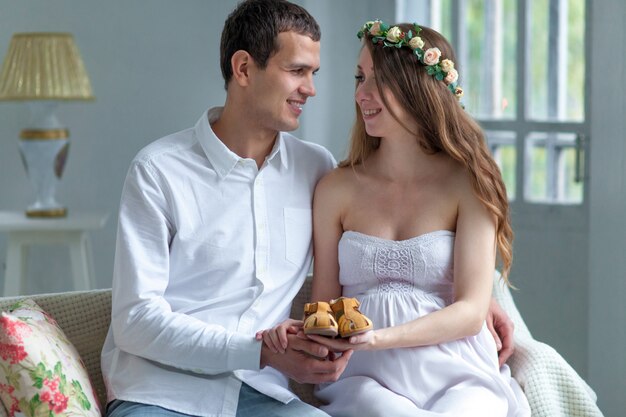 Cheerful young couple with baby shoes sitting at home