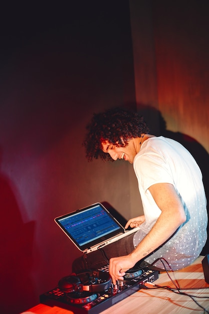 Free photo cheerful young dj spinning on turntable.