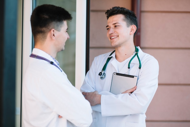 Cheerful young doctors at doors of hospital
