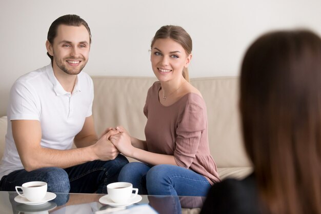 Cheerful young family couple on consultation. Holding hands and smiling