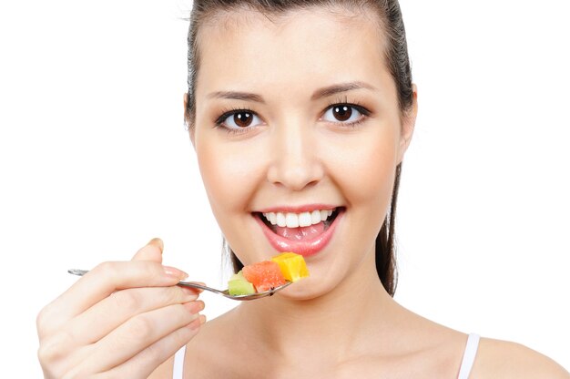 Cheerful young female face with spoon with pieces of fruits