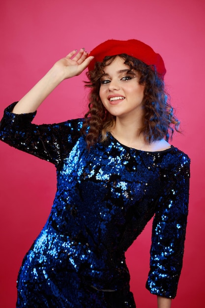 Cheerful young girl holding her hat and smiling on pink background High quality photo