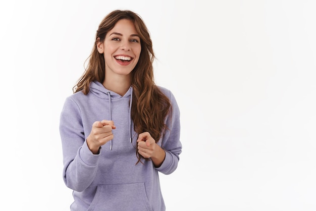 Cheerful young girl smiling broadly friendly carefree gaze pointing fingers camera amused have upbeat positive conversation congratulating you good job picking someone white background