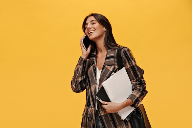 Cheerful young girl in stylish oversized jacket talks on phone