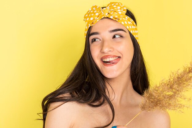 Cheerful young girls standing on yellow background and laughing