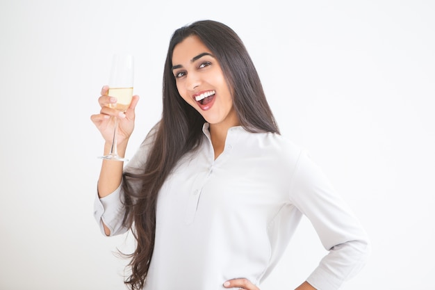 Free photo cheerful young indian woman raising glass of wine