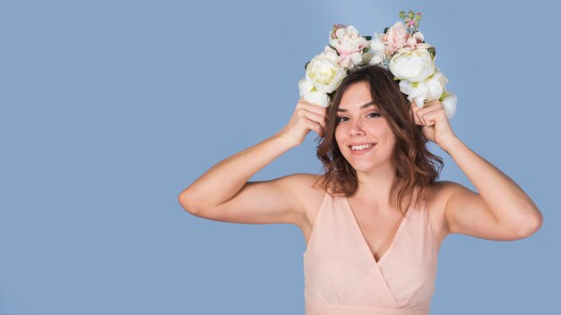 Cheerful young lady in dress with fresh flowers on head