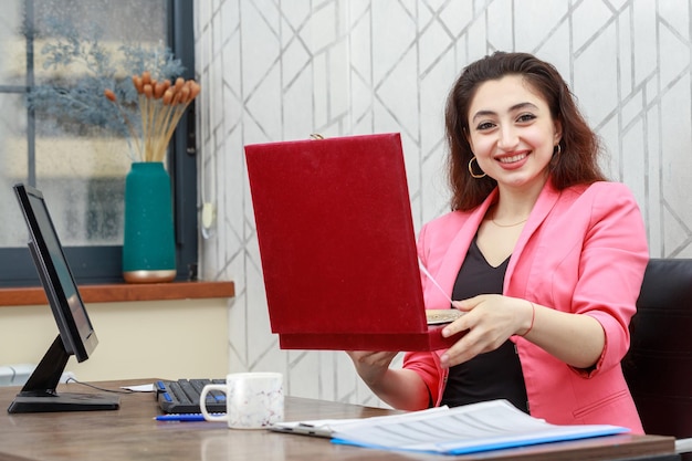 Cheerful young lady holding red gift box and laughing High quality photo