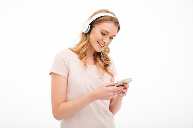 Cheerful young lady listening music using mobile phone.