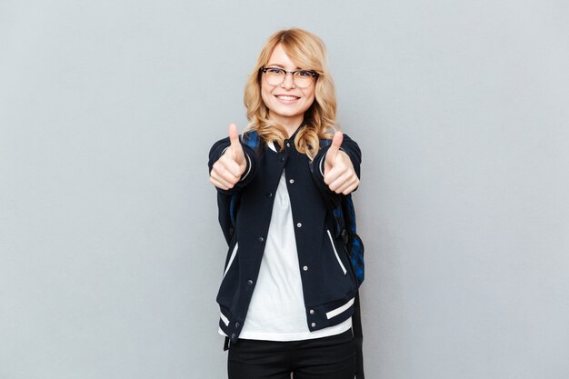 Cheerful young lady student showing thumbs up.