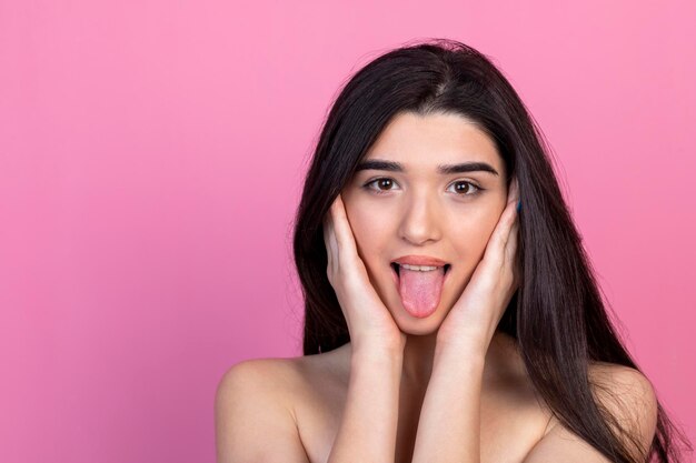 A cheerful young lady takes out her tongue and looking at the camera